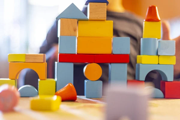 a child plays with colored wooden blocks at home.kid plays and builds buildings and towers with wooden colored blocks.