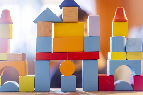 a child plays with colored wooden blocks at home.kid plays and builds buildings and towers with wooden colored blocks.