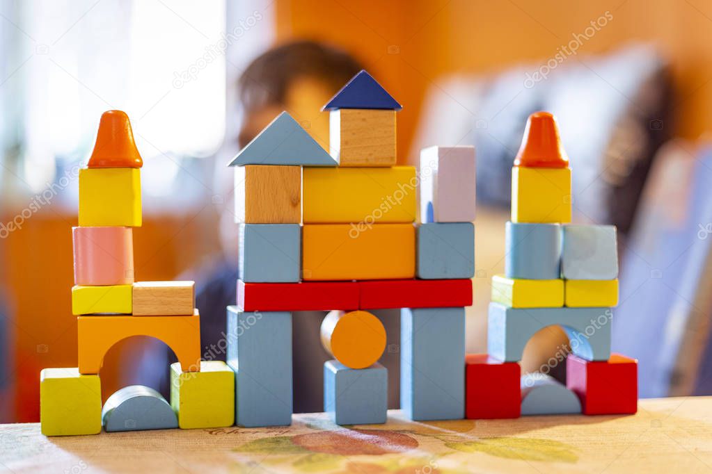 a child plays with colored wooden blocks at home.kid plays and builds buildings and towers with wooden colored blocks.