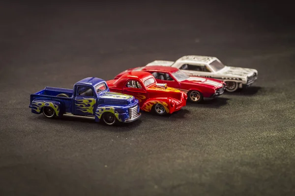 scale models of metal toy carts on a black background. colorful cars, different models and hot rods.