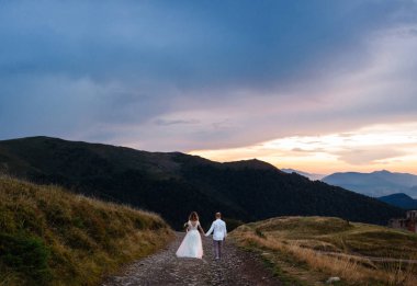 Güzel düğün çift, gelin ve damat, aşık dağların arka planda. Dağlarda düğün. Karpat dağlarının güzelliği, Ukrayna. Gün batımı zamanı