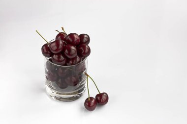 Olgun ve kırmızı kiraz hafif bir arka plan resmini içinde yüksek bir anahtar üzerinde açık bir cam halinde düzenlenir