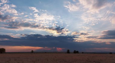 Çok büyük bir fırtına bulutu güneş ışığı altında dönüm güneşin sarı zemin üzerinde geç öğleden sonra kapalı