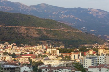 Budva modern şehir görünümünü arka planda bir deniz Körfezi ve batan güneşin parlak ışınları bir dağ Zinciri