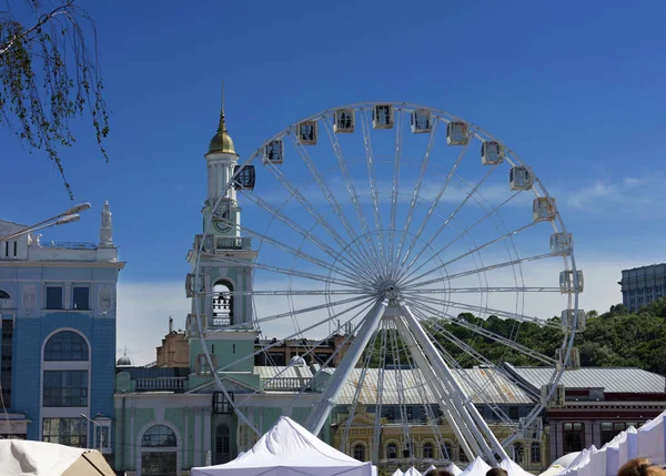 White Ferris wheel at Kontraktova Square on Podil in Kyiv against a clear blue sky
