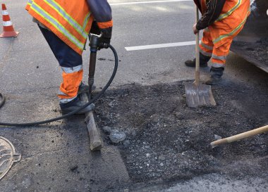 bir takım için yol bakım görevlileri'eski asfalt matkap ile kaldırır ve yol yapımında Ekskavatör sepeti içine kürek