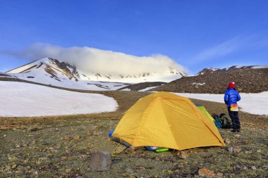 Turistler çadır Erciyes Dağı eteğinde yer alır, bir genç turist kız onu geri döndü ve kopya alanı sol tarafındaki dağın zirvesine bakar.