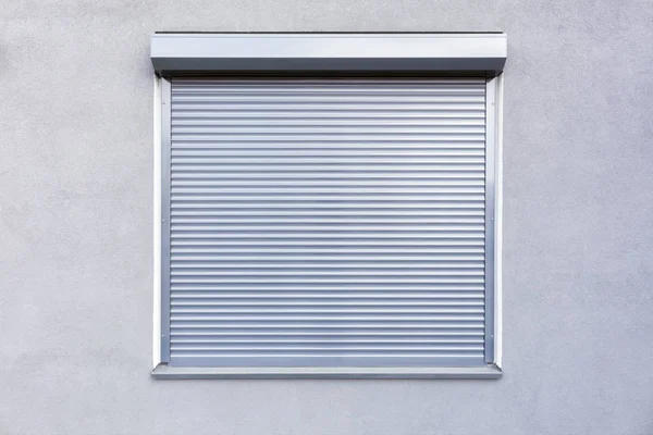 Light gray metal blinds on the windows of the facade of the house.