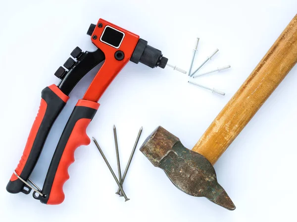 An old hammer with a wooden handle and a bunch of nails against new Rivet Gun and a bunch of Rivets