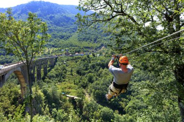 Bir turist üzerinde uzun bir teleferik bir dağ ve orman üzerinde haçlar taç Nehri.