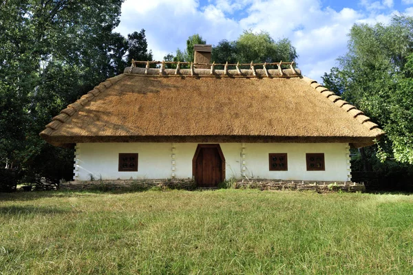 Antiga casa rural tradicional ucraniana com telhado de palha e cerca de vime no jardim — Fotografia de Stock