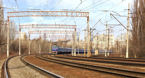 Пассажирские вагоны поезда на железнодорожных путях на фоне городского пейзажа — стоковое фото