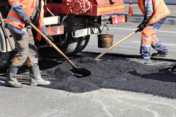 The working team renews a portion of asphalt with shovels in road construction