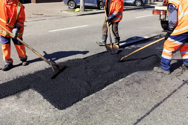 La brigada de trabajadores despeja una parte del asfalto con palas en la construcción de carreteras — Foto de Stock