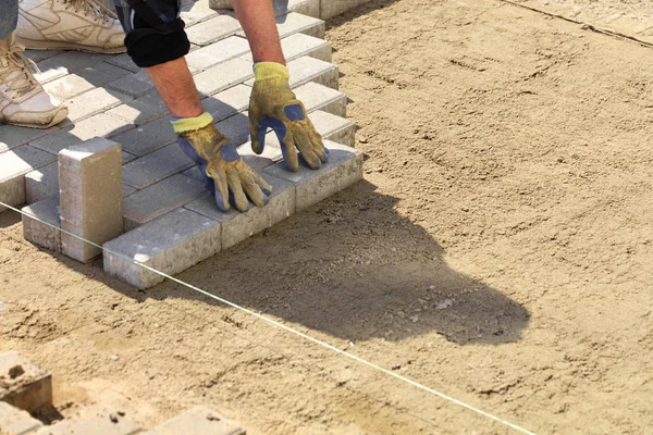 A munkavállaló meghatározza a járda-tábla a kész sík, homokos talajon a járdán. — Stock Fotó