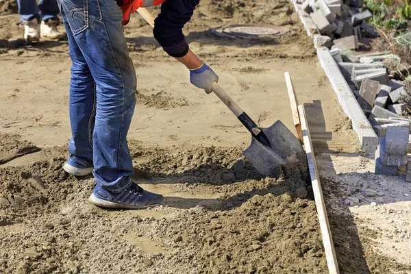 Работник с помощью лопаты дуб песок на деревянном уровне, чтобы выровнять фундамент . — стоковое фото
