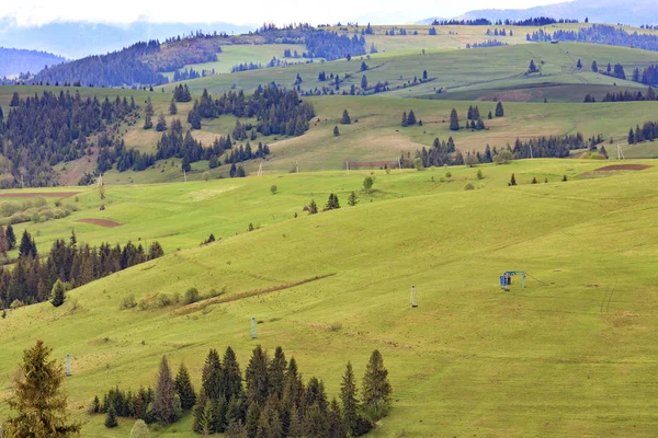 Landschap van de lente Karpaten met blauwe masten van een berg kabellift die naar de top van de berg leidt. — Stockfoto