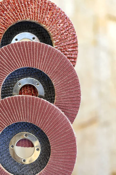 stock image Flap grinding wheels from different grains on wood and metal one on top of another vertical on a light beige background in unsharpness.