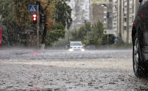 路上和人行道上的大雨浇在十字路口,浇水的汽车. — 图库照片