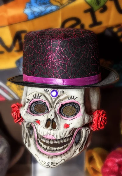 Halloween, skull doll with female makeup and a black-red hat, isolated on a blurred background.