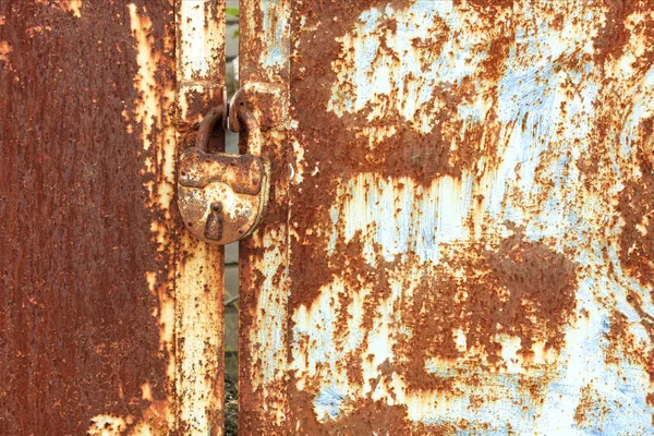 En gammal rostig lås förbinder en rostig grind. Rost på gamla plåt konsistens. — Stockfoto