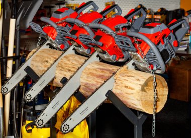 Büyük bir kütüğe saplanmış kırmızı güçlü elektrikli testereler karanlık bir arka plana karşı, profesyonel bahçe aracı kavramı.