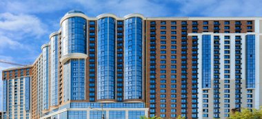 Modern konut binalarının panoramik görüntüsü cam mavi ve beyaz cepheli, mavi hafif bulutlu gökyüzüne karşı, kopyalama alanı olan resim.