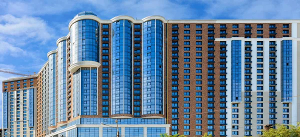 Modern konut binalarının panoramik görüntüsü cam mavi ve beyaz cepheli, mavi hafif bulutlu gökyüzüne karşı, kopyalama alanı olan resim.