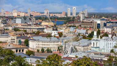 Yaz kenti Kyiv 'in eski Podolsky bölgesinin manzarası, dönme dolabı olan eski meydan ve yaldızlı kubbesi olan çan kulesi, Dnipro Nehri ve birçok şehir binası..