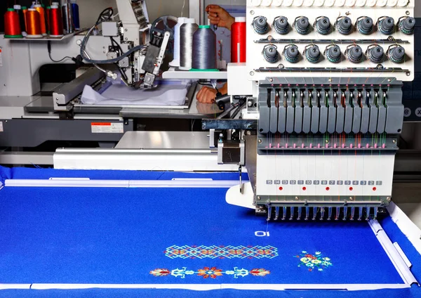 A modern professional embroidery machine for embroidery on various fabrics makes patterns with multi-colored spools of thread, space for text.