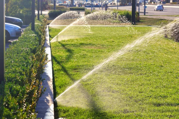 Automatic Irrigation System Multiple Sprinklers Irrigated Lawn Blurred Cityscape Bright — Stock Photo, Image