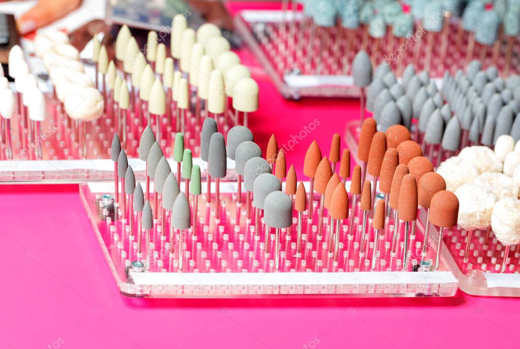 Medical instruments, nail cutters, grinding and polishing stones of various shapes and sizes of abrasive grain for manicure care. Color coding. Pink background, copy space.