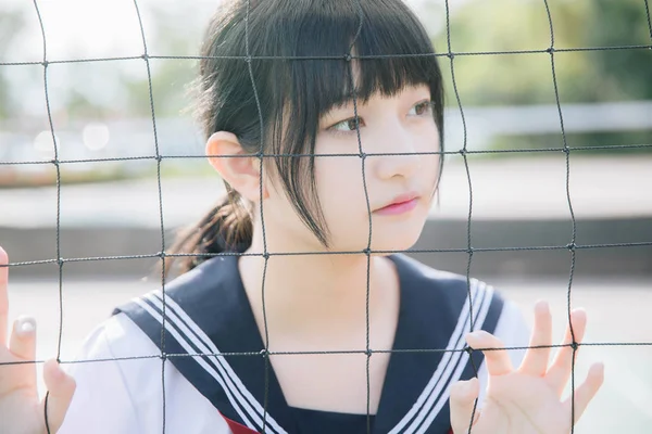 美しいですアジアの日本の高校生の女の子制服見ますとともにネットで緑の背景 — ストック写真