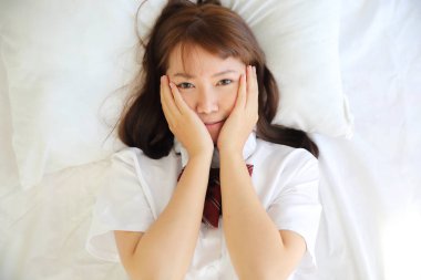 Portre Japon Okul uyuyan kız kostüm ve gülümseme beyaz sesi yatak odasında