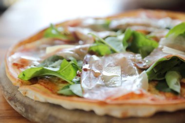 Pizza parma ham salata roket üzerinde ahşap masa arka plan ile domates sosu ile