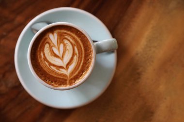Kahve dükkanının ahşap masasındaki sütten yapılmış kapuçino ya da Latte sanat kahvesi.