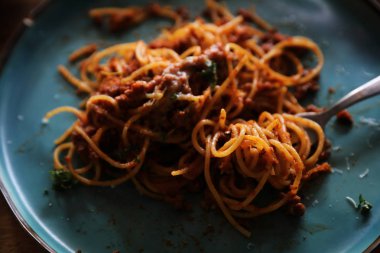 Parmesan peyniri ve fesleğenle süslenmiş kıyma ve domates soslu spagetti bolonez, İtalyan yemeği.