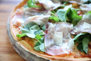 Pizza parma ham salata roket üzerinde ahşap masa arka plan ile domates sosu ile