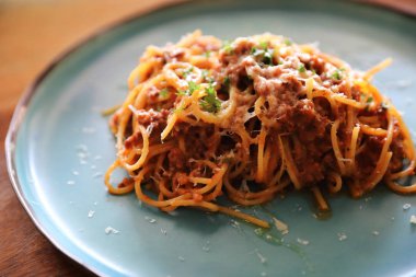 Parmesan peyniri ve fesleğenle süslenmiş kıyma ve domates soslu spagetti bolonez, İtalyan yemeği.