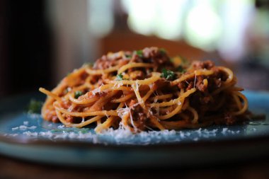Parmesan peyniri ve fesleğenle süslenmiş kıyma ve domates soslu spagetti bolonez, İtalyan yemeği.
