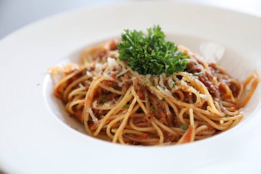 Parmesan peyniri ve fesleğenle süslenmiş kıyma ve domates soslu spagetti bolonez, İtalyan yemeği.