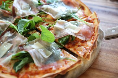 Pizza parma ham salata roket üzerinde ahşap masa arka plan ile domates sosu ile