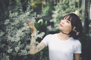 Beyaz gömlekli ve etekli Asyalı bir kızın portresi. Açık hava klasik film tarzına bakıyor.