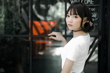 Beyaz gömlekli ve etekli Asyalı bir kızın portresi. Açık hava klasik film tarzına bakıyor.