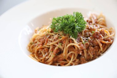 Parmesan peyniri ve fesleğenle süslenmiş kıyma ve domates soslu spagetti bolonez, İtalyan yemeği.