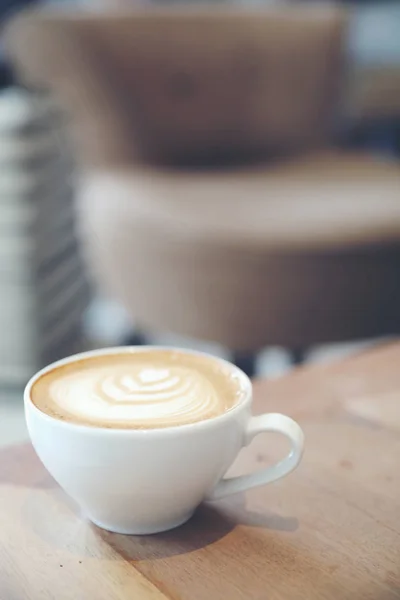 カプチーノかラテかコーヒーショップの木のテーブルの上のミルクから作られたアートコーヒー — ストック写真