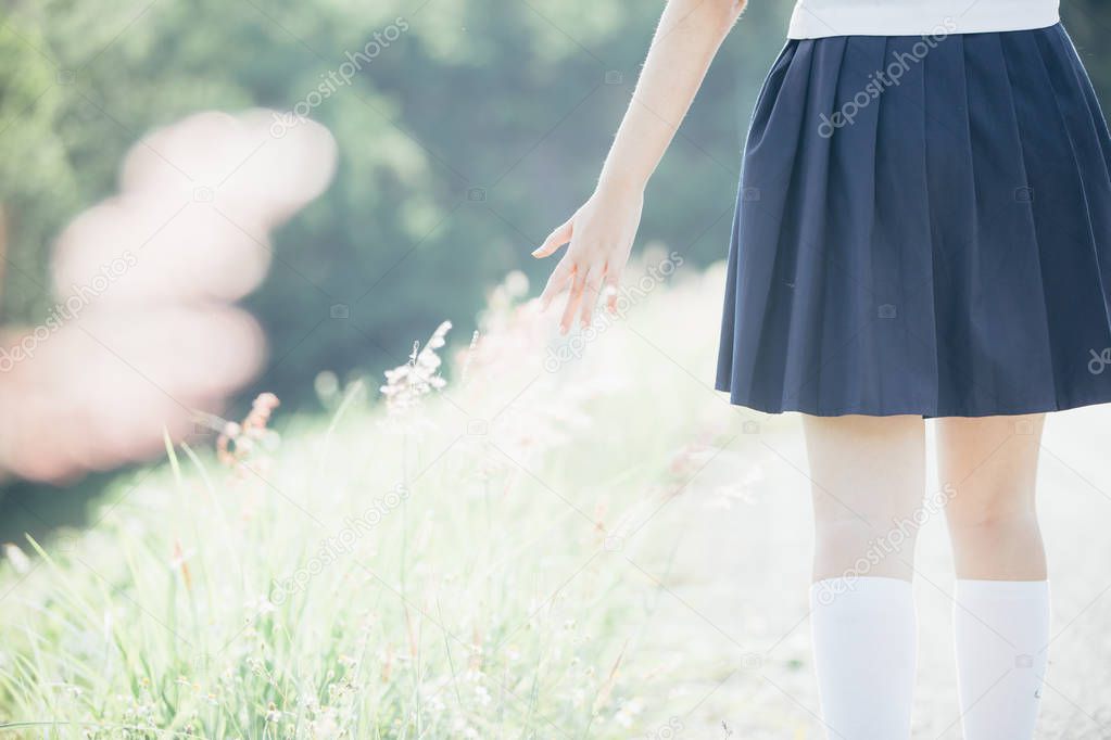 Portrait of asian japanese school girl costume walking with little flower at park outdoor film vintage style