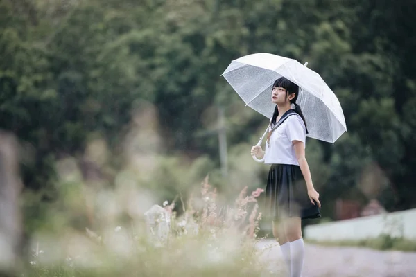 在雨中漫步在自然人行道上的亚洲学校女孩肖像 — 图库照片