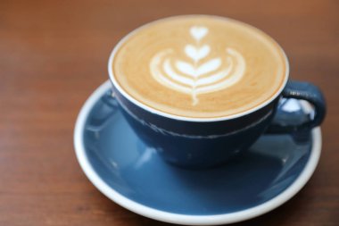 Kahve dükkanının ahşap masasındaki sütten yapılmış kapuçino ya da Latte sanat kahvesi.