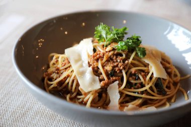 Parmesan peyniri ve fesleğenle süslenmiş kıyma ve domates soslu spagetti bolonez, İtalyan yemeği.